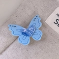 Gros plan d'une pince à cheveux papillon bleue avec détail coeur LOVE et strass brillants - Bleu