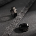 Close-up of black titanium steel ear clips with Greek pattern on dark rock background - Black Greek Fret