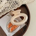 Macro detail of large beige acrylic hair claw clip with France Handmade text on wood - Yellow