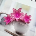 Pinza per capelli con tre fiori rosa traslucidi in resina lucida su una rivista - Rosa