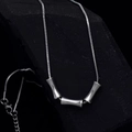 Silberne Schlangenkette mit drei Zylinderanhängern auf einem dunklen strukturierten Stein - 45+5cm