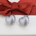 Detalle de los pendientes de corazón plateados con textura granulada y cinta roja de regalo - Stud aretes / Plateado