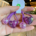 Dettaglio di elastici per capelli viola con ciondoli a cuore glitterati, qualità artigianale - Viola