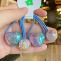 Dettaglio di tre elastici per capelli blu con ciondoli in resina a cuore e tondi - Celeste