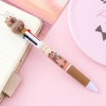 Simpatica penna a sfera a 4 colori Capybara con mascotte 3D su scrivania rosa pastello - Capibara Con Posate