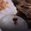 Close-up of heart-shaped dark red gemstone pendant in gold setting on a natural stone - Natural Garnet Heart Pendant Gold