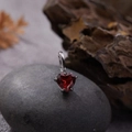 Detailed close-up of heart-shaped red gemstone pendant with silver four-claw setting - Natural Garnet Heart Pendant Silver
