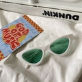 Close-up of retro white cat-eye sunglasses with green lenses on soft white fabric - Cat Eye / White Frame Green Lens