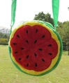 Detail of round watermelon plush crossbody bag with green strap on a grassy background - Red Watermelon
