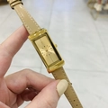Detailed close-up of a vintage rectangular gold watch with a beige leather strap - Gold Dial Light Coffee Leather Strap