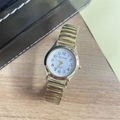 Top view of a gold-toned quartz watch with stretch band and white dial on wood background - Women's Watch / Gold Steel Strap White Dial