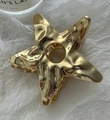 Detail of large gold star hair claw with hammered liquid metal texture on white paper - Gold