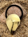 Detailaufnahme eines goldenen Tropfen-Metallanhängers an einem schwarzen elastischen Haargummi - Wassertropfen