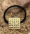 Detail eines schwarzen elastischen Haargummis mit einem quadratischen goldenen Metall-Charm - Quadratisch Hohl
