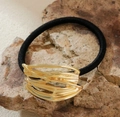 Detalle de un adorno de metal dorado ondulado en una goma de pelo negra sobre una base de piedra - Estilo 1-Ondulado Irregular