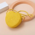Close-up of yellow heart-shaped straw woven mini bag for children with summer textures - Yellow