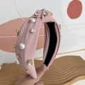 Close-up of pink fabric headband featuring white pearls and sparkling rhinestones - Pink
