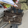 Retro large brown leather tote bag with buckle and key pendant shown in street style - Khaki
