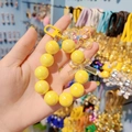 Close-up of yellow beaded charm with transparent bow and cute cartoon bear pendant - Yellow
