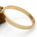Detail of gold bangle with Roman numeral engravings and a side clasp on a wooden stand - 8MM Roman Numerals Bangle Gold