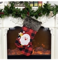 Dettaglio calza di Natale a quadri rossi e neri con Babbo Natale appesa al caminetto decorato - Babbo Natale