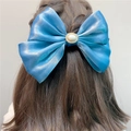 Blue satin double bow hair clip with pearl center worn on long brown hair back view - Spring Clips / Blue