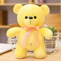Cute yellow plush teddy bear with a peach pink ribbon bow tie in a soft standing pose - Yellow