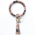 Close-up of leather keyring wristlet featuring dog pattern, fringe tassel and gold clasp - Cute Dog