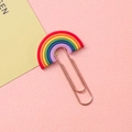 Creative rainbow shaped metal paper clip bookmark with colorful silicone top on pink surface - Rainbow