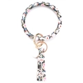 Close-up of black floral print PU leather bracelet keyring with long golden tassel - Peony