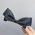 Detailed close-up of a black satin bow hair clip showing silk texture and metal spring - Spring Clips / Black