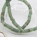 Close-up of 6x3mm green aventurine square abacus beads in a clear glass container - Green Aventurine