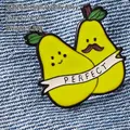 Detailed macro shot of alloy pear-shaped enamel brooch with PERFECT banner on denim - Pear