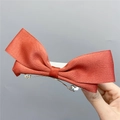 Detailed view of large orange ribbon bow hair clip with a sturdy metal spring base - Spring Clips / Caramel color