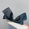 Detail of a black ribbon bow hair clip with silver alligator clip on a display card - Duckbill Hair Clips / Black