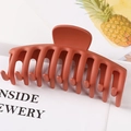 Close-up of a large reddish-brown matte plastic hair claw clip with multi-tooth design - Matte Brick Red