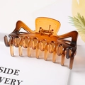 Detailed macro view of an amber resin hair claw clip with a geometric hollow butterfly design - Amber / 9.5CM