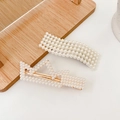 Set of two cream pearl hair clips with golden alloy base on a wooden tray - Silver Bell 2-Piece Set