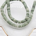 Green and white natural stone heishi disc beads on a gold-rimmed glass plate - Qinghai Jade