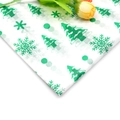 Close-up of Christmas tissue paper with green tree and snowflake prints on white - Christmas Tree