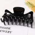 Detail of a large black glossy hair claw clip with a hollow geometric design on white paper - Black / 11.5CM