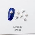 Détail macro de charmes d'ongles étoiles argentées 6x8mm avec strass sur ongles bleus - Style Étoile Scintillante à Quatre Branches Argentée (6681)