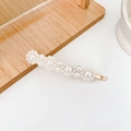 Elegant gold hair clip with wavy pearl design on a minimalist wooden base - Four Flowers