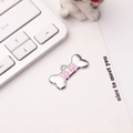 Detail of silver bone-shaped dog tag with a pink paw print on a white display card - 30*15mm / Pink