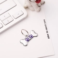 Detail of bone-shaped silver metal dog tag with purple paw print on white background - 30*15mm / Purple