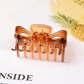 Close-up of amber brown translucent hair claw clip with interlocking teeth and metal spring - Amber / 6cm