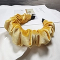 Detail of yellow velvet pleated headband on a vintage magazine and white ceramic plate - Yellow