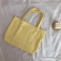 Sac fourre-tout en toile jaune vif posé sur tissu blanc avec bougie décorative - Light jaune