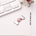 Close-up of bone-shaped silver dog tag with red enamel paw prints on a white background - 30*15mm / Red