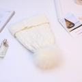 Close-up of cable knit beanie with large white faux fur pompom and ribbed cuff - White